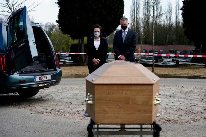 Empleados de la funeraria Bouvy, en Bruselas, usan elementos de protección y toman otras medidas preventivas durante un funeral de una víctima de covid-19, que se lleva a cabo sin familiares del fallecido ni ningún asistente por cuestiones de seguridad.