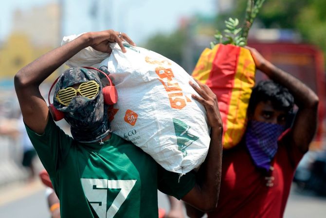 En Chennai, India, el hombre que usa anteojos en forma de corazón y tiene la cara cubierta por una máscara, transporta un saco de vegetales cerca de un mercado en la ciudad en medio del temor a la propagación del nuevo coronavirus durante un cierre nacional impuesto por el gobierno como medida preventiva contra el coronavirus el 11 de abril de 2020.