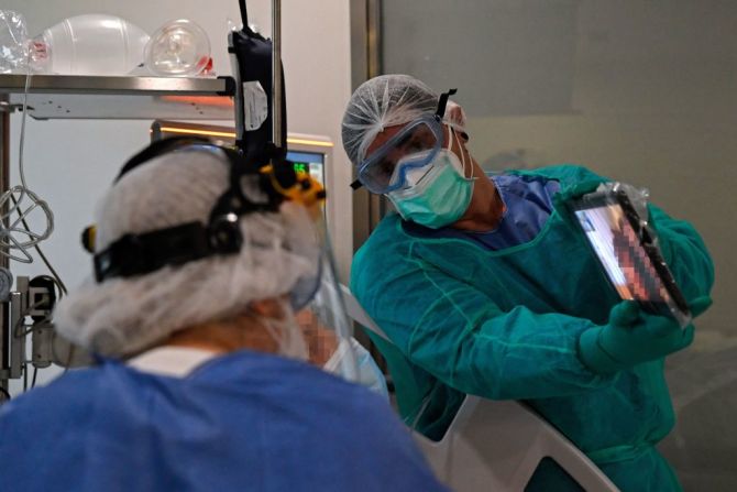 Trabajadores de salud del Hospital Ramón y Cajal de Madird, España, sostienen una tablet frente a un paciente con covid-19 internado en una unidad de cuidado intensivo para una videollamada con sus familiares el 14 de abril de 2020. España superó las 18.000 muertes por coronavirus y llega a los 178.000 casos de contagiados.