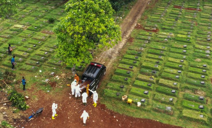 Esta foto aérea tomada en Jakarta, Indonesia, el 15 de abril de 2020, muestra trabajadores de sanidad, trasladando un ataúd de una víctima por covid-19 a un cementerio.