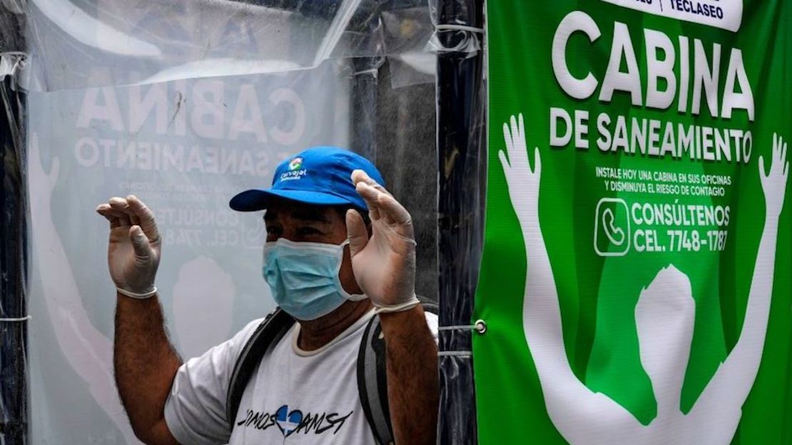 Un hombre pasa por una cabina sanitaria instalada por el municipio en la entrada de un mercado para evitar la propagación del coronavirus en Santa Tecla, El Salvador.