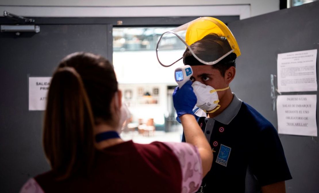 Un trabajador de salud le toma la temperatura corporal a un empleado del Aeropuerto Internacional de Santiago, en Santiago de Chile, el 20 de abril de 2020, durante la pandemia del coronavirus.