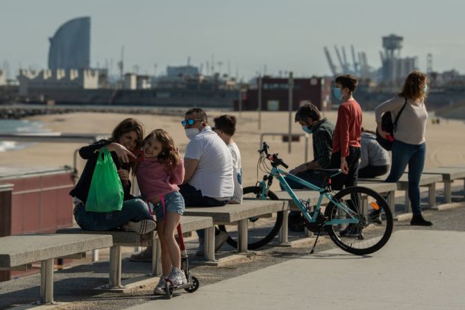 Niños y adultos miran el Mediterráneo sentados en la playa La Mar Bella en Barcelona.