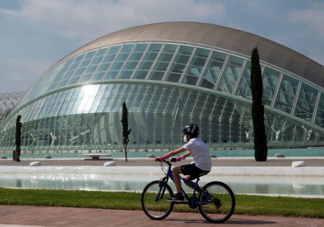 Un niño monta en bicicleta frente a la Ciudad de las Artes y las Ciencias en Valencia.