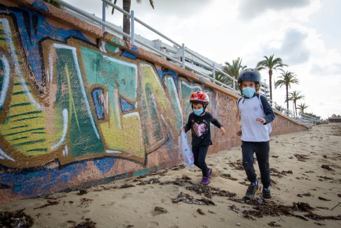 Dos niños corren por la playa Portixol en Palma de Mallorca.