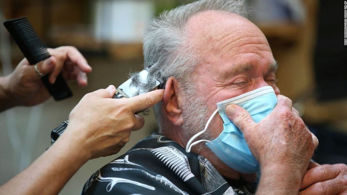 Lonnie Sullivan se cubre la cara con una máscara mientras se cortaba el pelo en The Barber Shop en Broken Arrow, Okla., El viernes 24 de abril de 2020. La tienda fue una de las varias a las que se le permitió reabrir debido a la relajación de las restricciones relacionadas con el coronavirus.