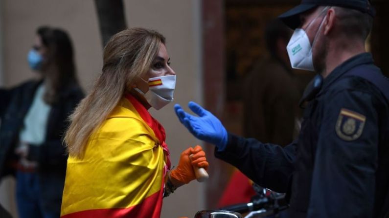 Un agente de policía habla con una mujer durante una protesta contra el gobierno por su gestión de la crisis del coronavirus en Madrid. GABRIEL BOUYS/AFP via Getty Images