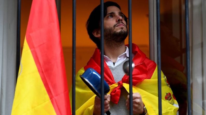 Un hombre envuelto con una bandera española golpea una olla durante una protesta contra el gobierno por su gestión de la crisis del coronavirus, a pesar de las medidas de confinamiento para evitar la propagación de la enfermedad.. GABRIEL BOUYS/AFP via Getty Images