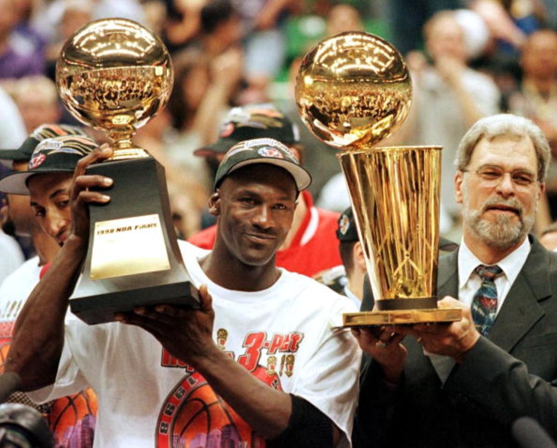 Michael Jordan con el sexto trofeo de 'MVP' de una final, junto al exentrenador de los Bulls Phil Jackson y el trofeo de campeón de la NBA.