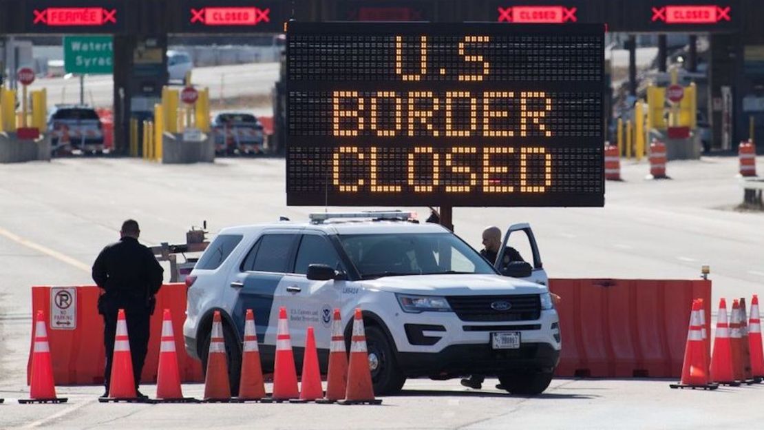 US Customs officers stand beside a sign saying that the US border is closed at the US/Canada border in Lansdowne, Ontario, on March 22, 2020. - The United States agreed with Mexico and Canada to restrict non-essential travel because of the coronavirus, COVID-19, outbreak and is planning to repatriate undocumented immigrants arriving from those countries. (Photo by Lars Hagberg / AFP)