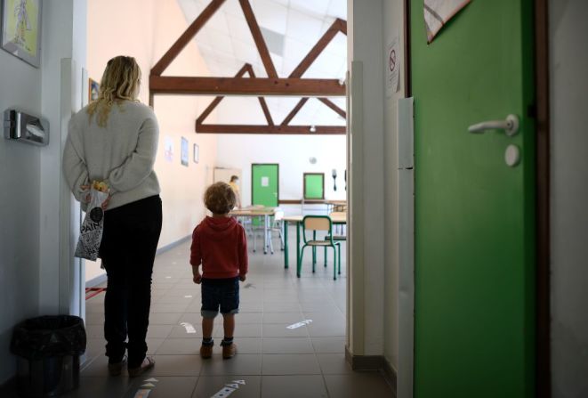 Un niño ve las flechas de movimiento para mantener la distancia social dentro de un salón de clases en Clairefontaine-en-Yvelines, cerca de París, Francia.