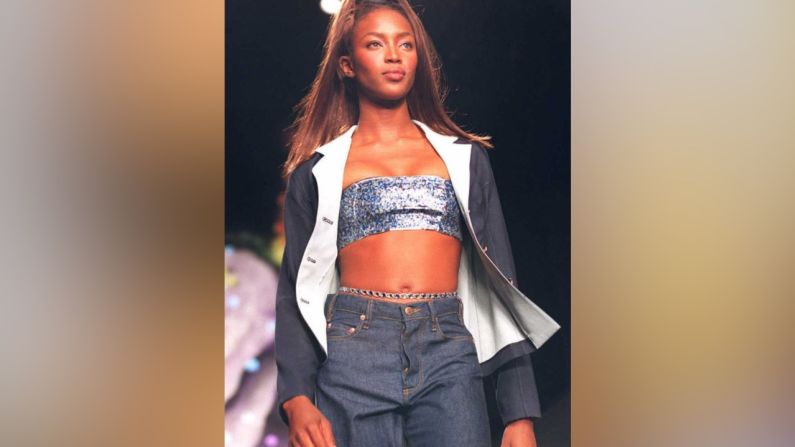 La modelo Naomi Campbell desfiló en múltpiles pasarelas, aquí modela usa una chaqueta vaquera con pantalones a juego sobre un bra de tubo de lentejuelas para la colección de moda Todd Oldham Spring 1997 en la Semana de la Moda.