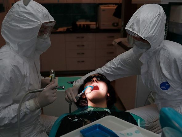 La dentista Dora Gemesi y su asistente, Time Raksi-Csuhai, trabajan en un paciente en Budapest, Hungría, el 18 de mayo. Fue el primer día que reabrieron las prácticas dentales en el país. Laszlo Balogh / Getty Images