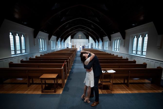 Los recién casados Tyler y Caryn Suiters se abrazan después de casarse en Arlington, Virginia , el 18 de abril. El reverendo Andrew Merrow y su esposa, Cameron, fueron los únicos otros asistentes a la ceremonia debido a las pautas de distanciamiento social. Win McNamee / Getty Images