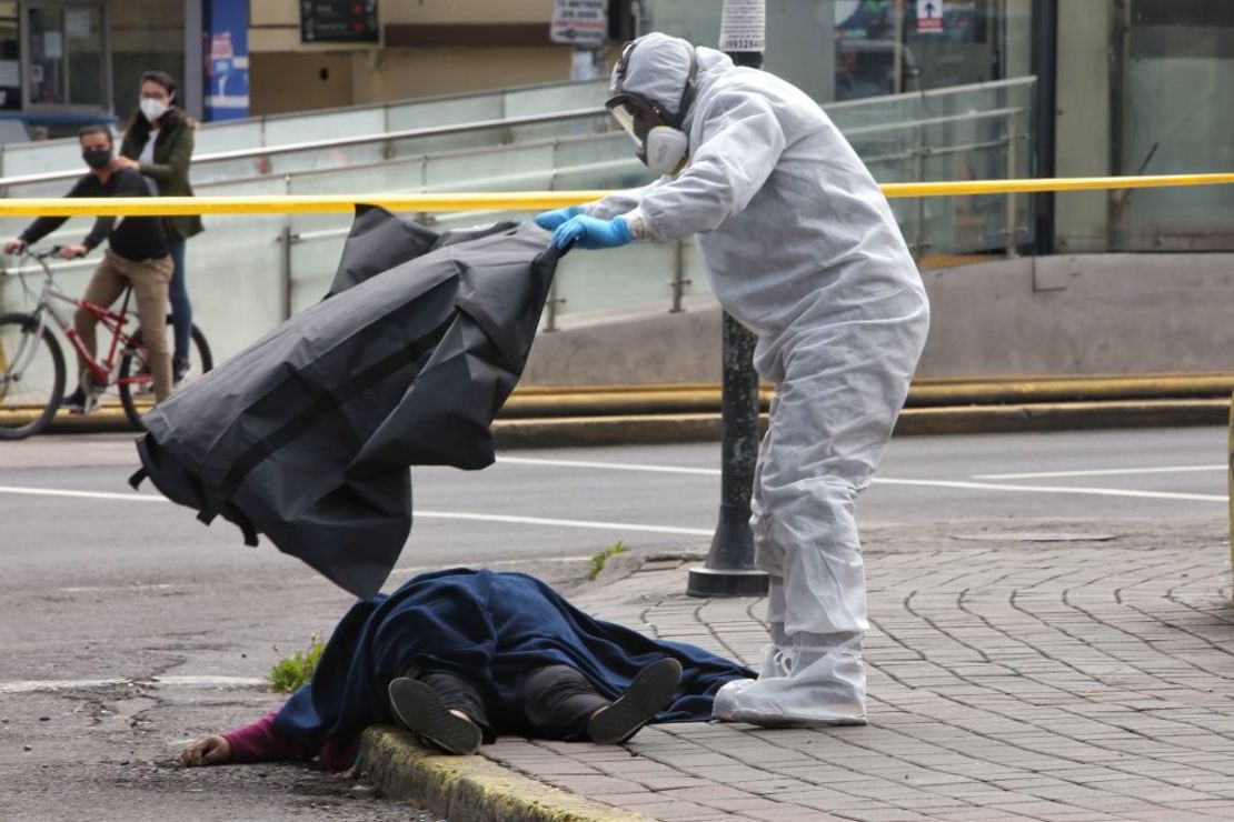 Policía científica de Ecuador cubre el cuerpo de una mujer que murió por causas desconocidas en medio de la pandemia en Quito, Ecuador.