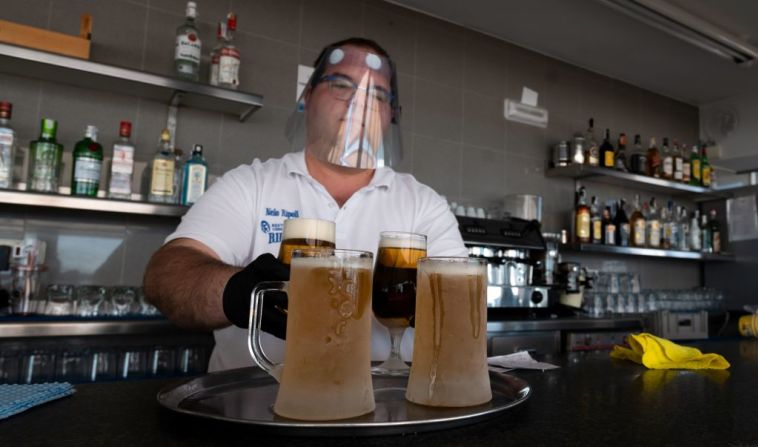 Mesero cumple las medidas de seguridad para entregar dos cervezas en una terraza de la playa Malvarrosa, en Valencia, el 19 de mayo. JOSE JORDAN/AFP via Getty Images)