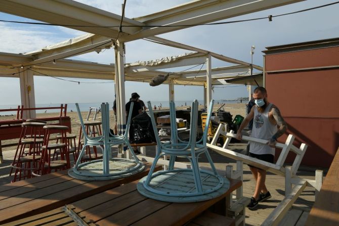 Empleados organizan las mesas en una terraza frente a la playa de la Barceloneta, en Barcelona.