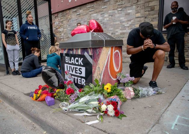 Personas se reúnen y rezan alrededor de un monumento improvisado cerca del sitio donde Floyd fue llevado a la policía custodia el día anterior. Elizabeth Flores / Star Tribune / AP