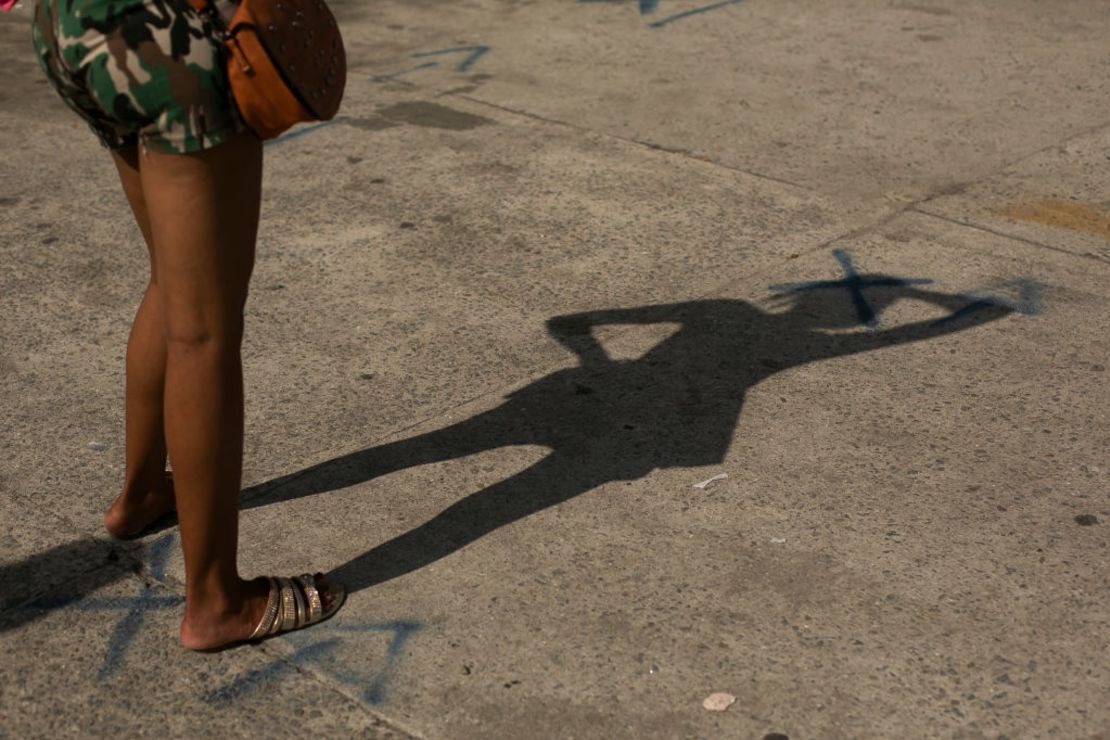 Una mujer en Río de Janeiro, Brasil, se para sobre una de las marcas en el pavimento que indican a las personas que deben conservar la distancia.