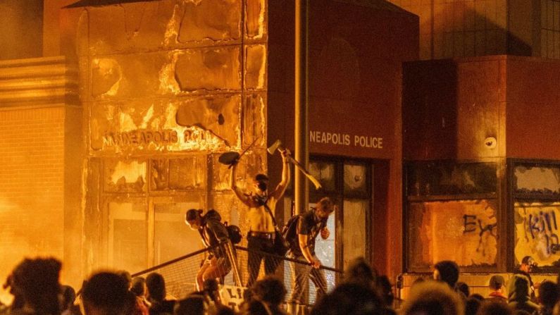 Las llamas iluminan la fachada de una estación de policía de Minneapolis, donde el 28 de mayo los manifestantes en contra de la muerte de Floyd protestaron sobre barricadas.