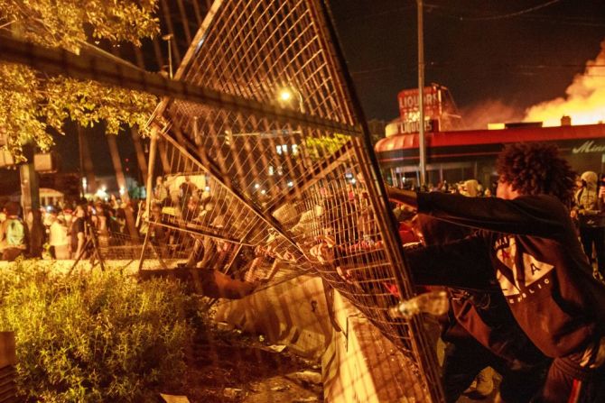 Personas empujan una puerta de una estación de policía de Minneapolis, en protesta por la muerte de Floyd.