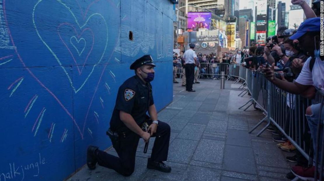 Un policía de la ciudad de Nueva York se arrodilla durante una manifestación en Times Square.