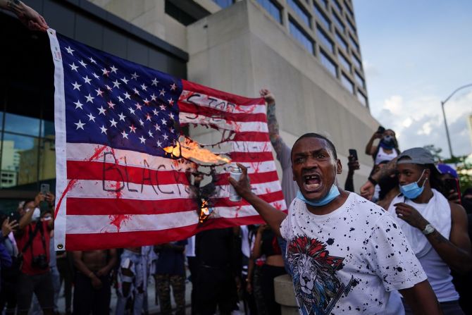 Los manifestantes queman una bandera frente al Centro CNN en Atlanta el viernes. Elijah Nouvelage / Getty Images