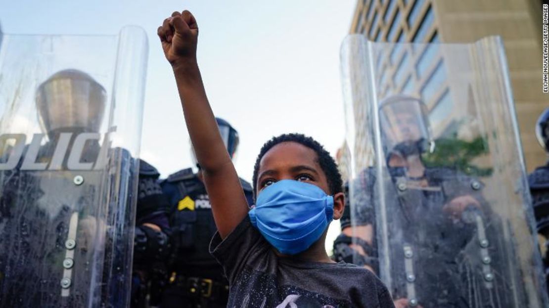 Un niño levanta el puño para una foto de un amigo de la familia durante una manifestación por la muerte de George Floyd en Minneapolis mientras estaba bajo custodia policial, el 31 de mayo de 2020, en Atlanta, Georgia.