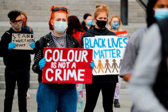 "El color (de piel) no es un crimen", dice este cartel de una manifestante en la plaza Trafalgar en el centro de Londres. Al fondo, otro cartel, con Black Lives Matter, el 5 de junio de 2020.