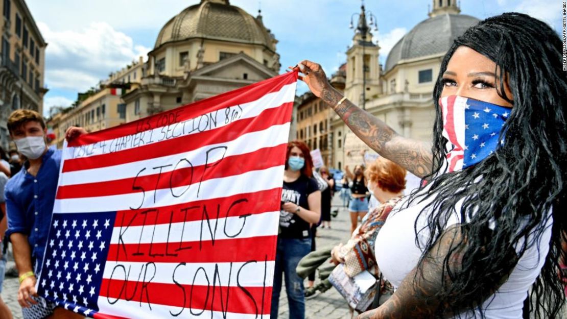 Manifestantes sostienen una bandera estadounidense al revés en Roma.