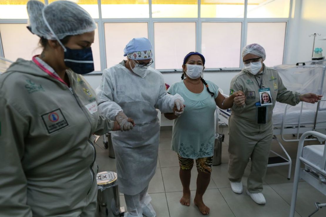 Health workers assist a COVID-19 patient at the Gilberto Novaes Municipal Hospital in Manaus, Brazil on June 8, 2020. - The hospital has a new wing dedicated exclusively to give medical attention to indigenous patients infected with COVID-19. (Photo by MICHAEL DANTAS / AFP)