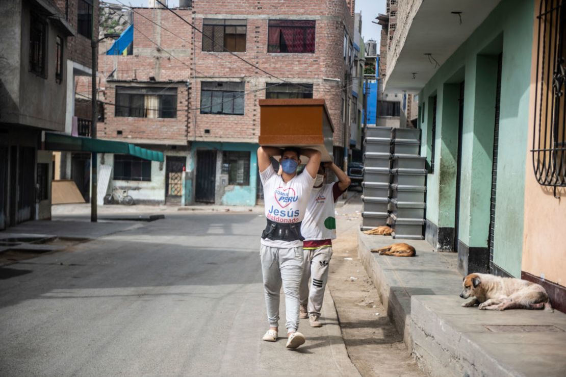 TOPSHOT - Workers carry a coffin made of Mapresa (pressed wood) to be stored at a factory at Juan de Lurigancho district in Lima, on June 4, 2020 amid the COVID-19 coronavirus pandemic. - While the Peruvian economy has been semi-paralyzed for 80 days due to the pandemic, coffin maker Genaro Cabrera has quadrupled his sales. (Photo by Ernesto BENAVIDES / AFP)