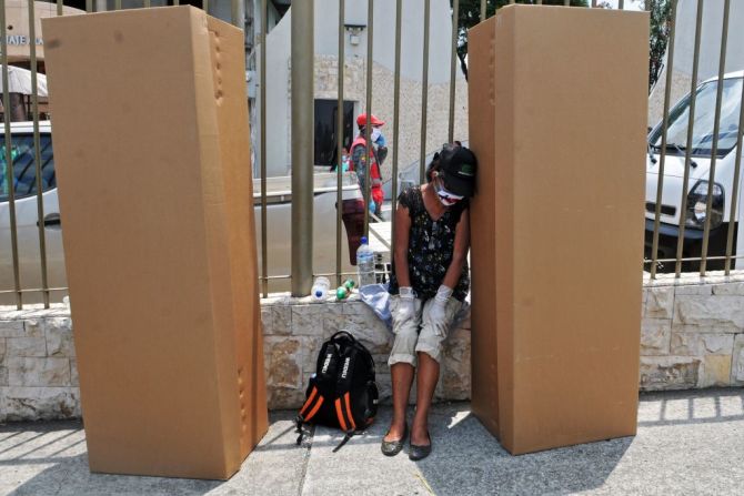 Una mujer usa un tapabocas junto a dos ataúdes hechos de cartón fuera del cementerio de Guayaquil, Ecuador.