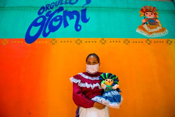 Maricela Pérez, del grupo indígena Otomí, usa un tapabocas mientras carga una muñeca artesanal en Ciudad de México.