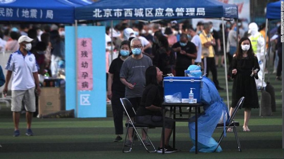 Un trabajador de la salud que usa un traje protector toma una prueba de hisopo de una mujer en un centro de pruebas establecido para personas que visitaron o viven cerca del mercado de Xinfadi en Beijing.