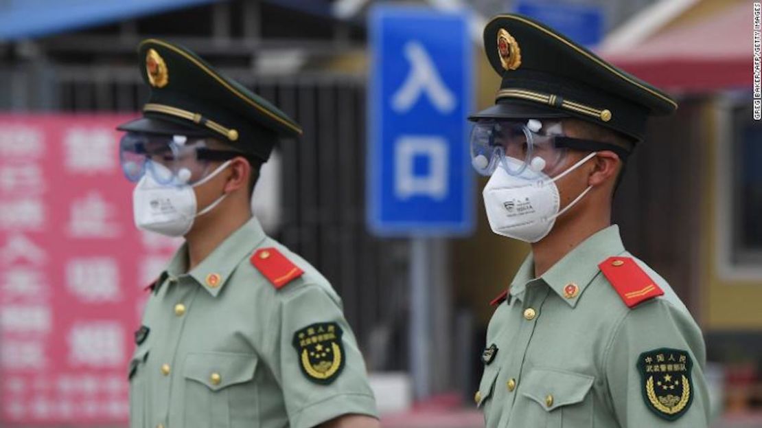 Agentes de la policía paramilitar usan máscaras faciales y gafas protectoras mientras hacen guardia en una entrada al mercado cerrado de Xinfadi en Beijing el 13 de junio de 2020.