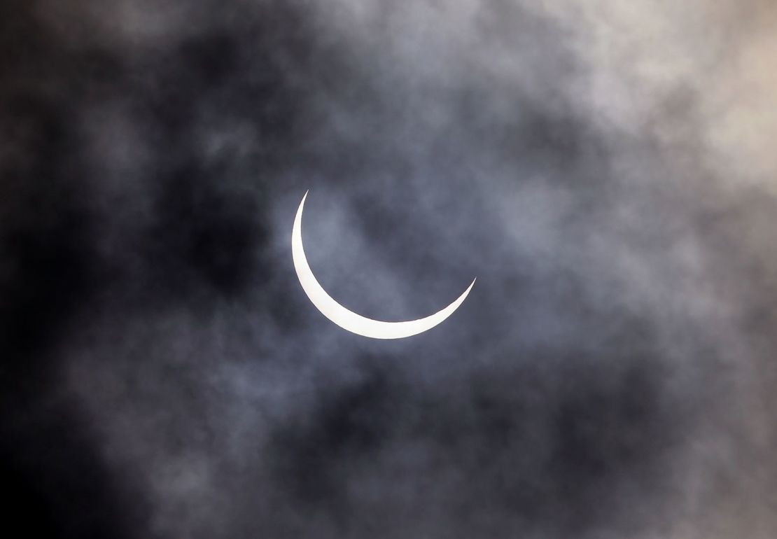 El Sol se ve a través de las nubes de lluvia durante un eclipse solar en Nueva Delhi, India.