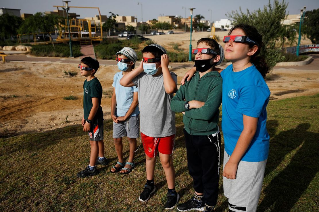 Unos niños usan anteojos protectores especiales mientras observan el eclipse solar parcial desde Yeruham, Israel.