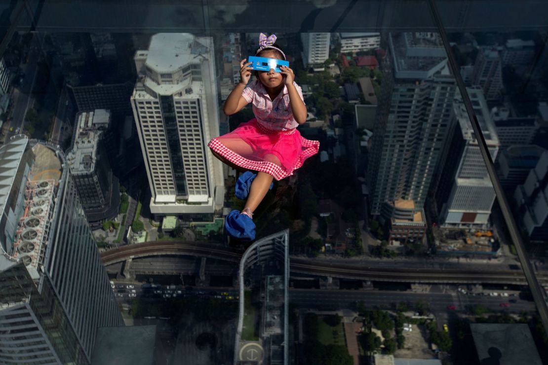 Una niña observa el eclipse en en el Mahanakhon Skywalk Tray en el edificio King Power Mahanakhon en Bangkok, Tailandia.