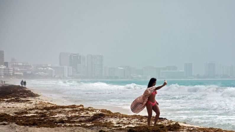 Una turista se hace una selfie en la playa de Cancún, México, mientras la nube de polvo sahariano nubla el cielo.