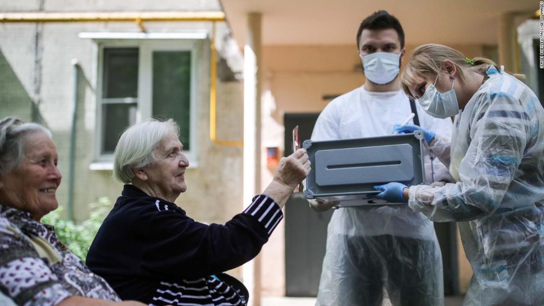 Una mujer muestra su pasaporte a una integrante de la mesa de votación.