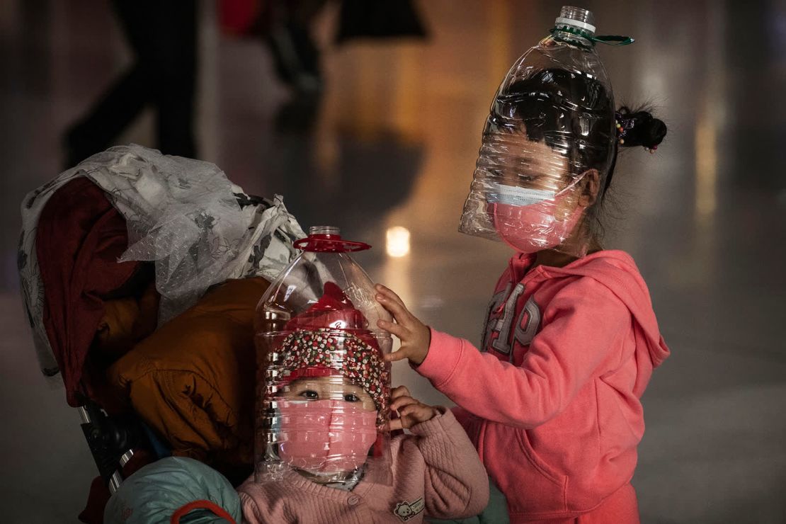 Niños usan botellas plásticas como mascarillas improvisadas mientras esperan registrarse en un vuelo en el aeropuerto de Beijing el 30 de enero. El uso de máscaras faciales se ha extendido en muchos países a medida que las personas tratan de ayudar a frenar la propagación del coronavirus.