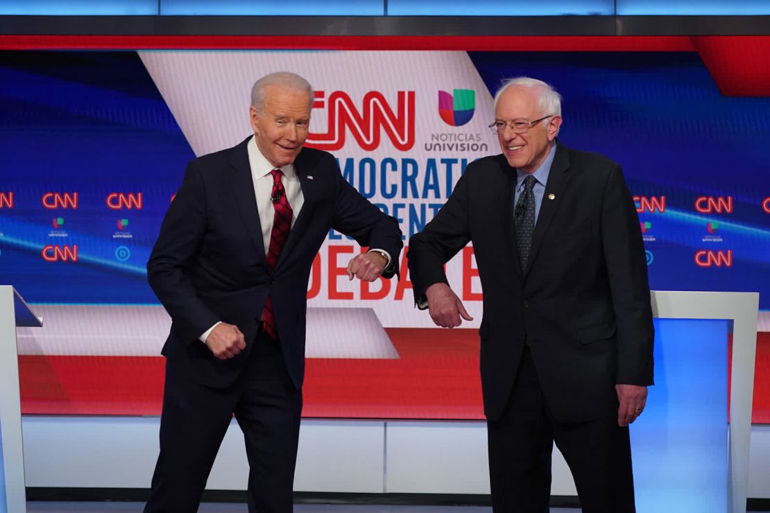 El exvicepresidente Joe Biden, a la izquierda, saluda al senador estadounidense Bernie Sanders con un golpe en el codo antes de un debate en la ciudad de Washington el 15 de marzo. Este fue el primer debate individual de la temporada de primarias, y sucedió en circunstancias sin precedentes. Se suponía que el debate se realizaría en Arizona frente a una audiencia en vivo, pero por la pandemia de coronavirus tuvo lugar en la capital de la nación sin audiencia.