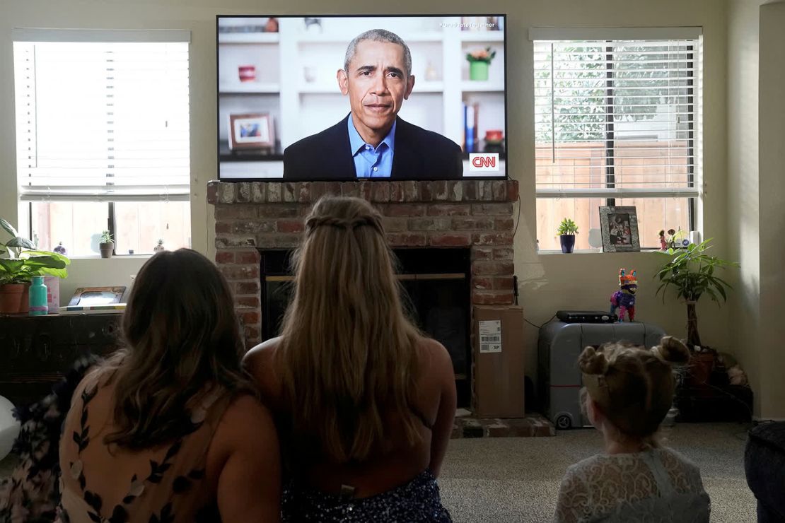 La estudiante de secundaria de San Diego Phoebe Seip (en el centro) y sus hermanas Sydney (a la izquierda) y Paisley ven al expresidente de Estados Unidos Barack Obama pronunciar un discurso virtual para millones de estudiantes de último año de secundaria el 16 de mayo (Bing Guan/Reuters).