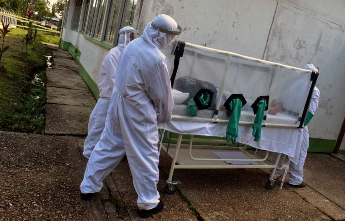 Trabajadores médicos llevan a un paciente de covid-19 en una camilla hecha con plástico, tubos y guantes de cocina en Puerto Nariño, en el Amazonas colombiano, en la frontera con Perú.