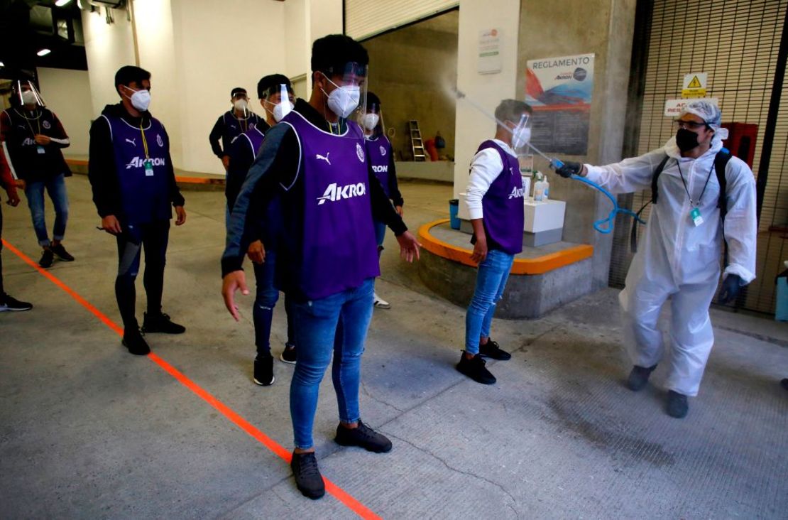 Un trabajador desinfecta a un recogepelotas en un partido de fútbol entre Guadalajara y Atlas en Guadalajara.