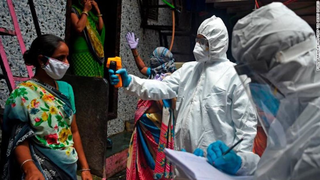 Voluntarios médicos con equipos de protección personal toman la temperatura de una mujer dentro del barrio pobre de Dharavi, en Mumbai, el 9 de julio de 2020.