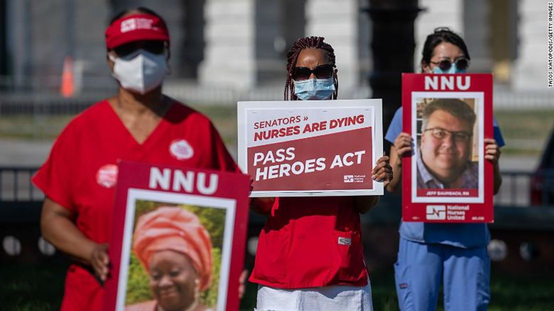 Enfermeras sostienen carteles de colegas que han muerto por coronavirus, mientras participan en una vigilia pública frente al Capitolio de Estados Unidos.