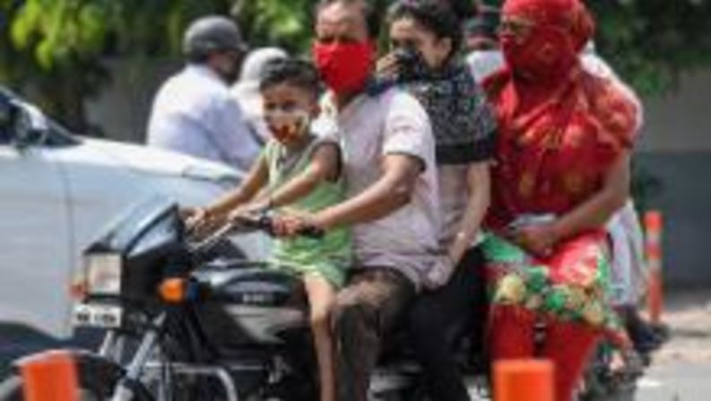 India: un niño y un hombre usan máscaras faciales mientras viajan con su familia en una motocicleta en Amritsar el 8 de julio. Narinder Nanu / AFP / Getty Images