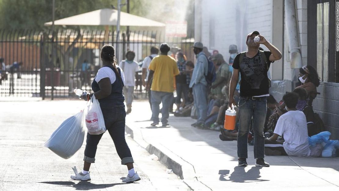 Las personas que no tienen vivienda o tienen inseguridad de vivienda reciben agua, alimentos y alivio de calor en Andre House en Phoenix el 11 de julio de 2020. La pandemia está obligando a las ciudades a cambiar la forma en que mantienen a los residentes a salvo del calor extremo.